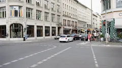 Menschen gehen auf Gehweg neben Straße mit Fahrzeugen und Gebäuden bei Tageslicht
