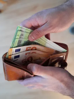 Mann zählt 50-Euro-Scheine aus seinem Geldbeutel