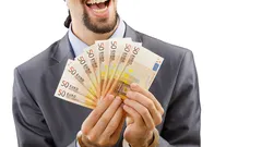 Mann im Anzug hält lächelnd mehrere 50-Euro-Scheine in der Hand